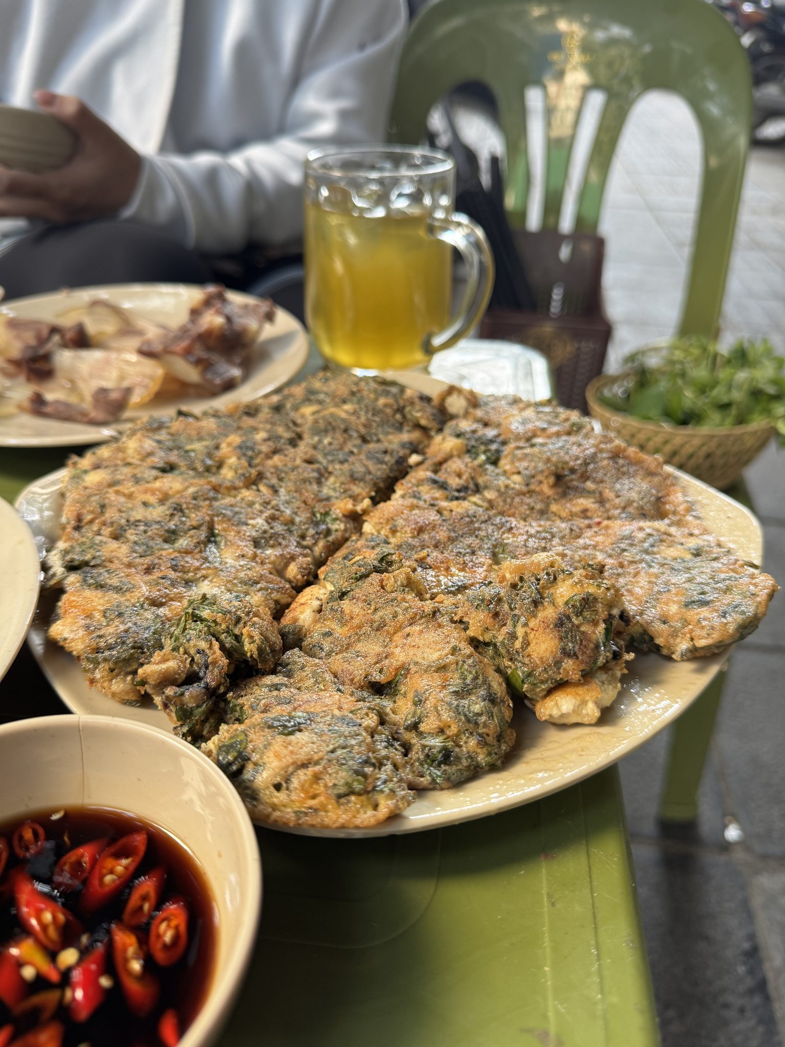 Golden-fried egg patties flecked with dark green mugwort leaves, glistening with oil.